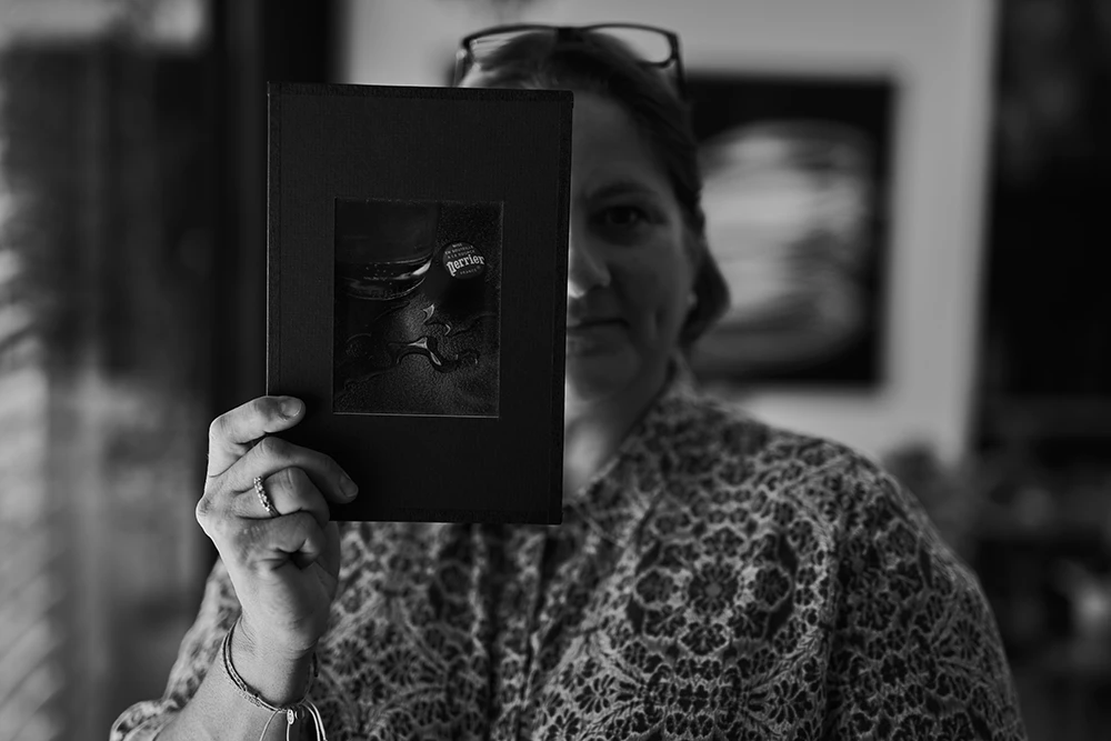 Chantal Lamarre hält eines ihrer Fotos in einem schwarzen Passepartout vor ihre rechte Geschichtshälft
